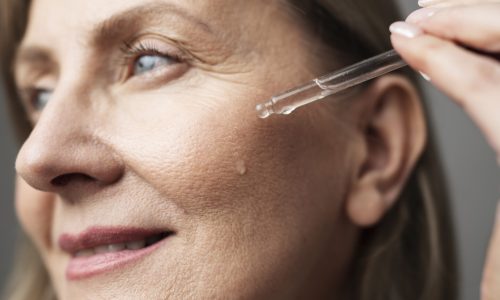 close-up-smiley-senior-woman-using-serum